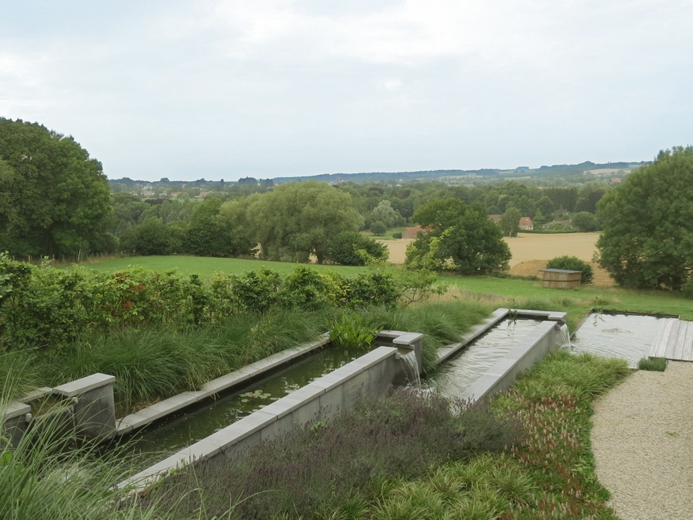 Succession de bassins-canal en cascades servant également de soutènement pour asseoir le talus de terre arrière. Structures maçonnées et parement en pierre bleue belge.